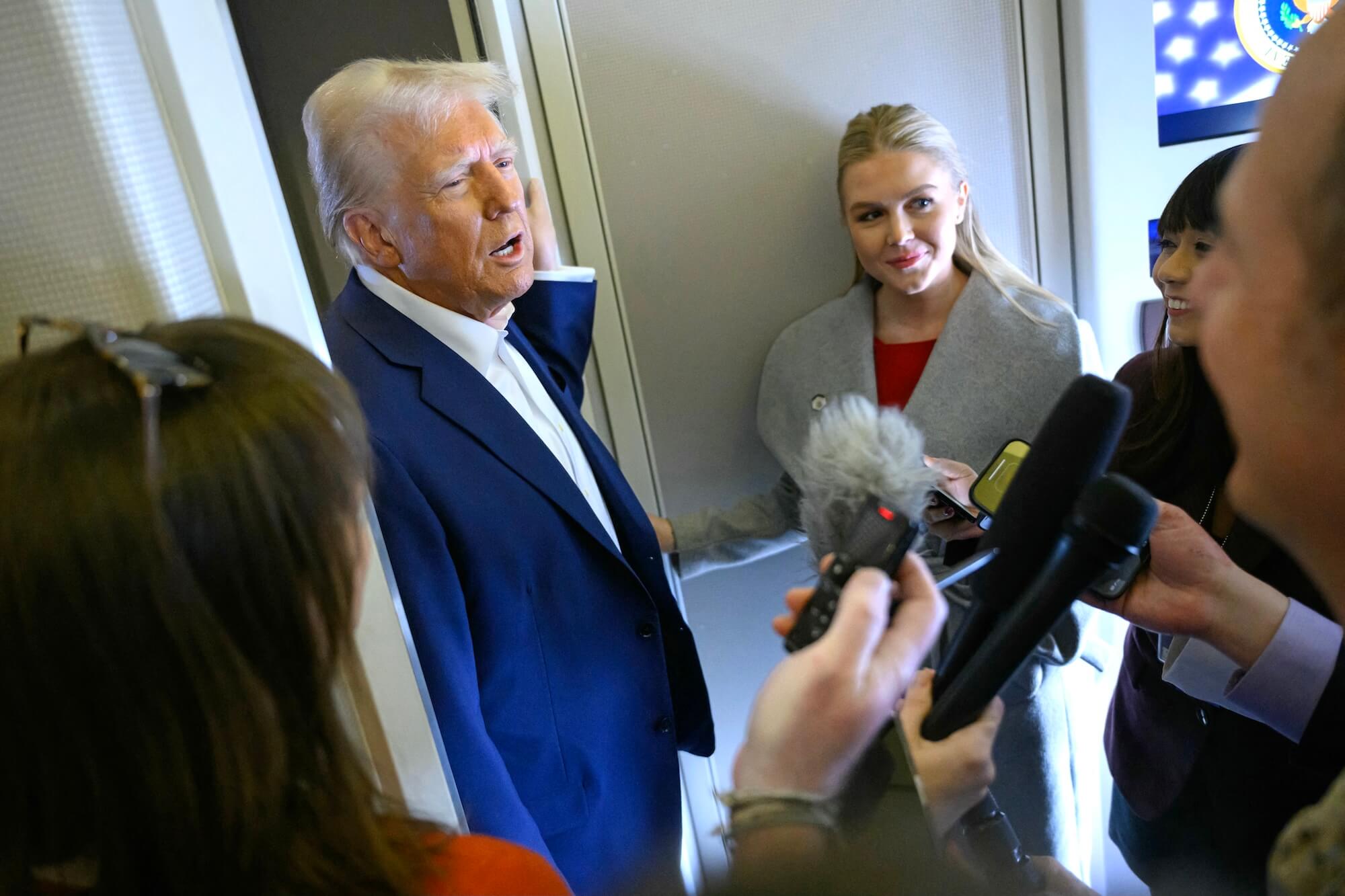 US-Präsident Donald Trump spricht an Bord der Air Force One nach dem Abflug von Las Vegas nach Miami mit der Presse. Neben ihm steht die Pressesprecherin des Weißen Hauses, Karoline Leavitt (r.).
