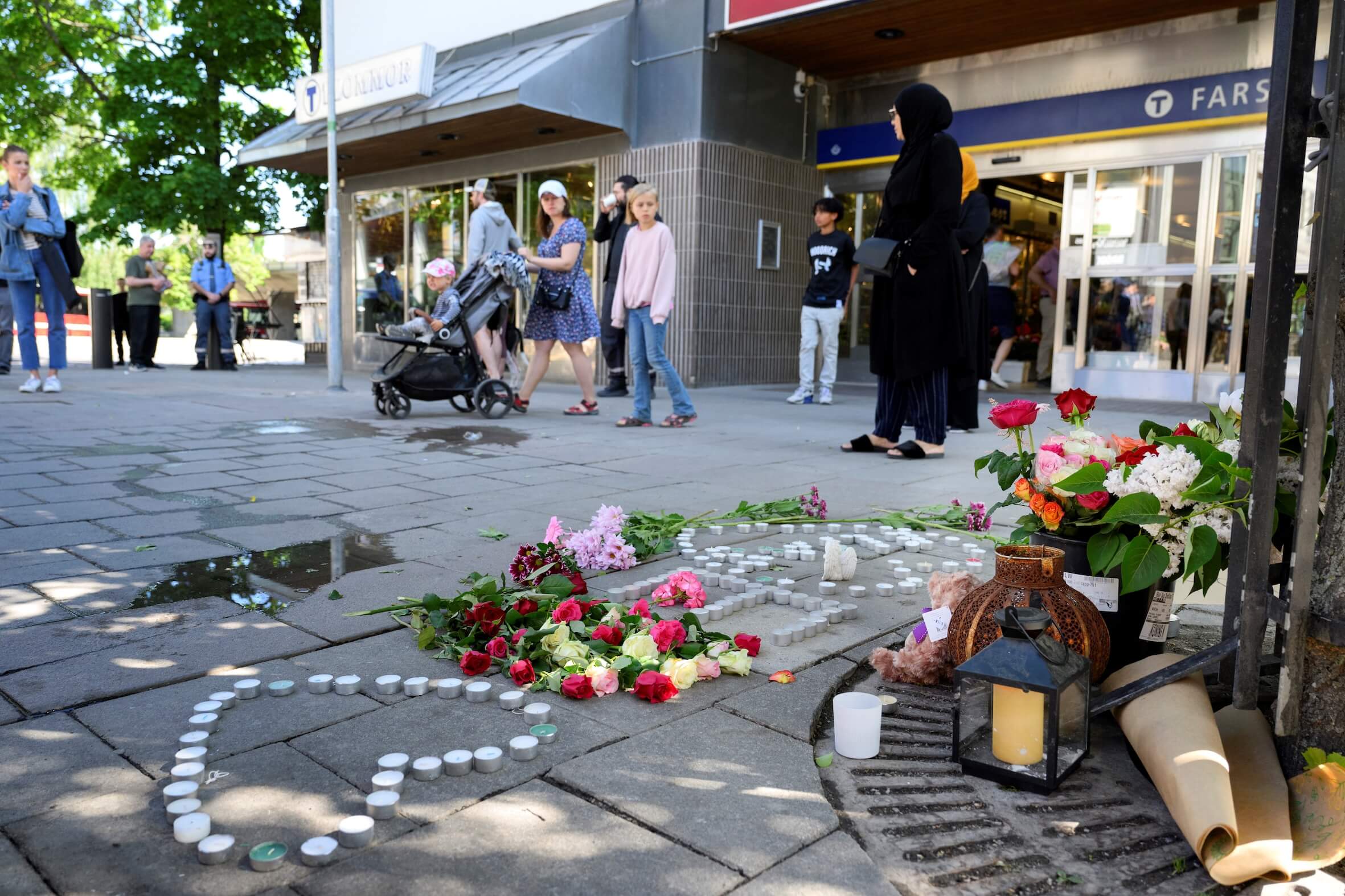 Blumen und Kerzen liegen am Tag nach der Schießerei im Einkaufszentrum Farsta südlich von Stockholm am 10. Juni 2023 auf dem Bürgersteig. Ein Bub (15) starb und drei Menschen wurden schwer verletzt.