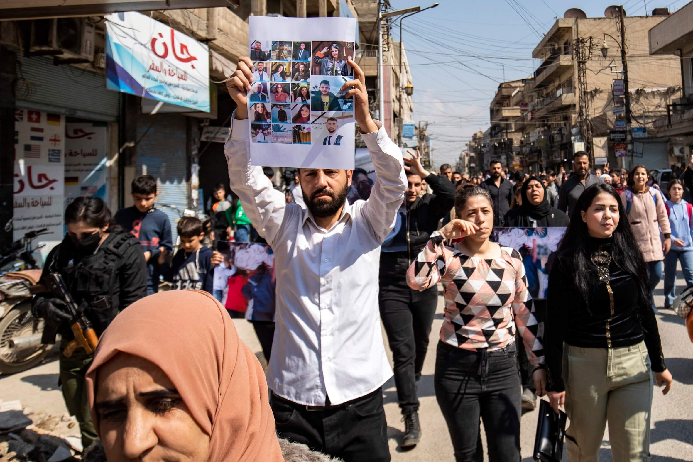 Ein Mann trägt ein Plakat mit einer Collage von Bildern der Opfer der jüngsten Gewaltwelle gegen die alawitische Minderheit während einer Protestkundgebung.