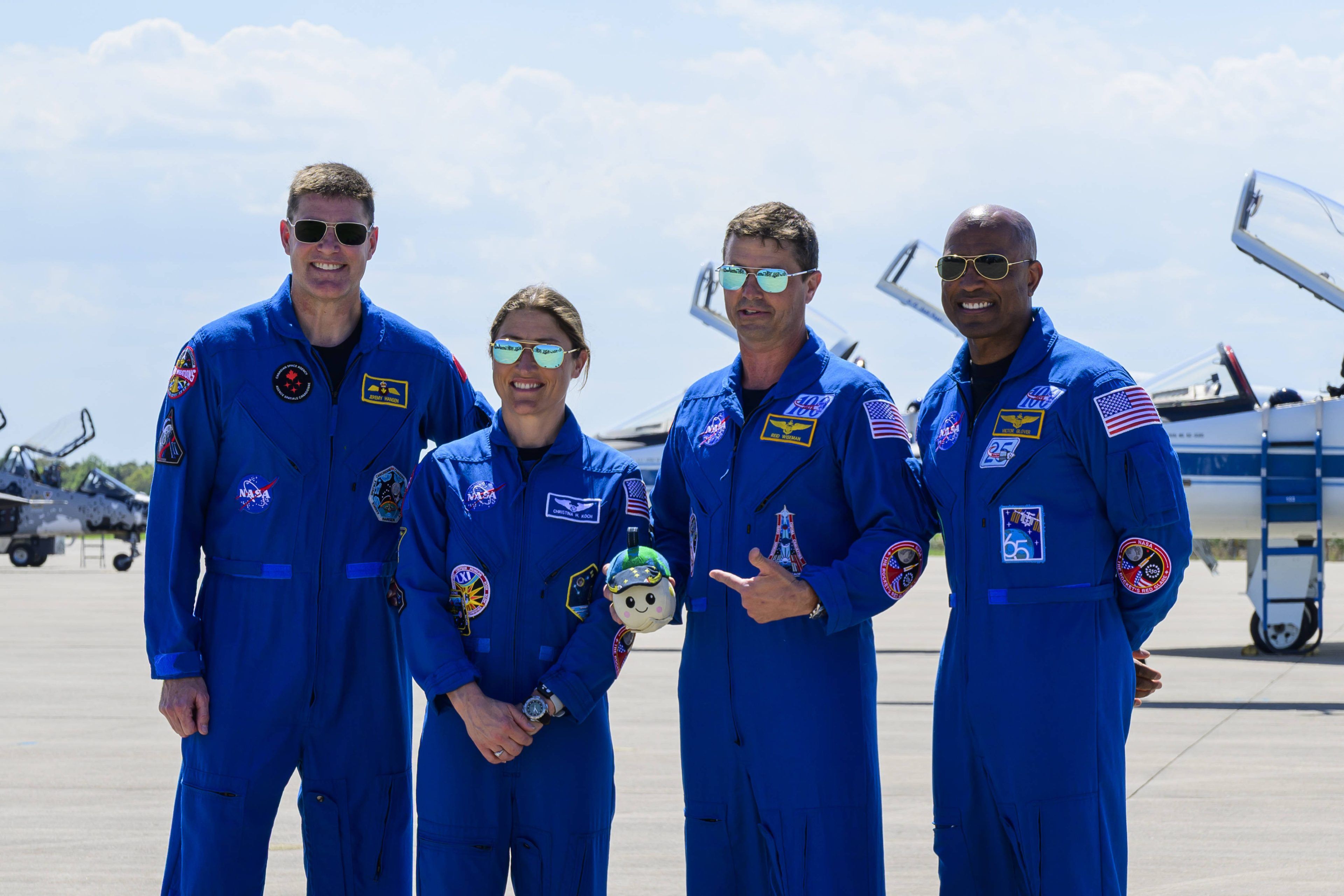 Reid Wiseman, Christian Koch, Jeremy Hansen und Victor Glover werden von Maskottchen